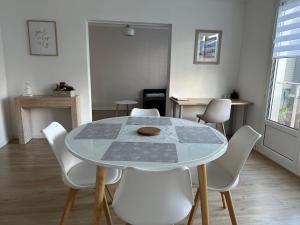 a dining room with a table and white chairs at Appartement Dunkerque proximité plage et centre ville in Dunkerque