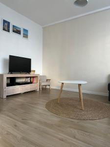 a living room with a table and a tv at Appartement Dunkerque proximité plage et centre ville in Dunkerque