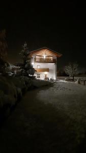 Una casa se ilumina por la noche en la nieve en Il giardino di Anna en Fai della Paganella