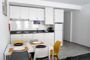 eine Küche mit weißen Schränken sowie einem Tisch und Stühlen in der Unterkunft Almada Downtown 202 in Porto