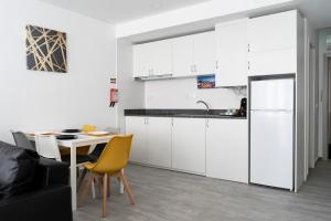 a kitchen with white cabinets and a table and yellow chairs at Almada Downtown 202 in Porto
