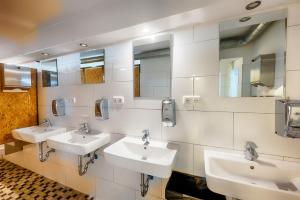 ein Bad mit 3 Waschbecken und Spiegeln an der Wand in der Unterkunft Hostel Westlight in Hamburg