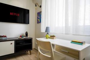 a room with a white desk and a tv on the wall at Mediterranea Apartment- CENTRAL STATION - FREE WIFI&NETFLIX in Bari