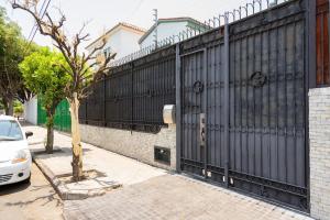 a black fence with a tree next to a car at Casa Mateo in Guadalajara