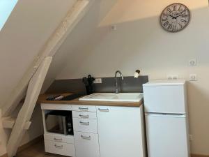 a kitchen with a sink and a clock on the wall at Luzerne in Châteauroux