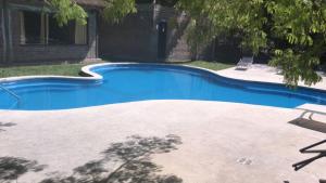- une piscine bleue dans une cour avec une maison dans l'établissement Armonía, à Victoria