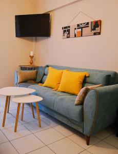 a living room with a blue couch and two tables at Cozy studio, 1min from Kamara in Thessaloniki