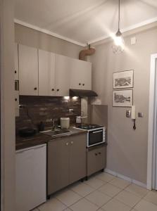 kuchnia z białymi szafkami, zlewem i kuchenką w obiekcie Cozy studio, 1min from Kamara w Salonikach
