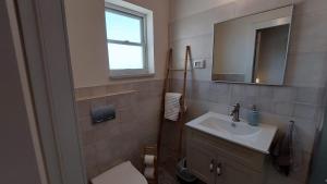 ein Badezimmer mit einem Waschbecken, einem Spiegel und einem WC in der Unterkunft הבית ליד המצוק By The Cliff in Mitzpe Ramon