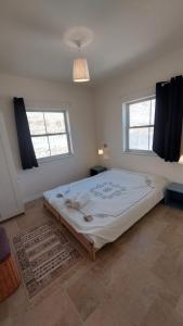 un grande letto in una stanza con due finestre di הבית ליד המצוק By The Cliff a Mitzpe Ramon