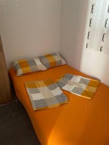 2 łóżka w małym pokoju z pomarańczową pościelą w obiekcie Apartman Edi w Nin