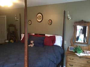 un dormitorio con una cama con un osito de peluche sentado en ella en Guest Suites at Willowgreen Farm, en Summerside