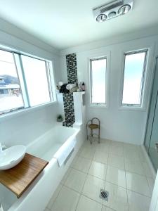 a white bathroom with a tub and a sink at Diggers Beach Villa Coffs Harbour in Coffs Harbour