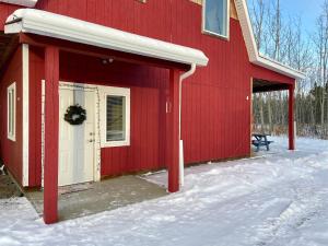 a red barn with a white door in the snow at The Big Red Barn in Whitehorse