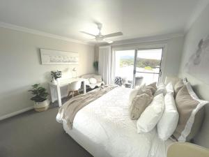 1 dormitorio con 1 cama blanca grande y ventana en Diggers Beach Villa Coffs Harbour en Coffs Harbour