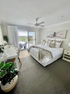 a white bedroom with a large bed and a window at Diggers Beach Villa Coffs Harbour in Coffs Harbour