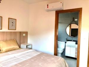 1 dormitorio con cama, aseo y espejo en Apto c otima localizacao e WiFi Pocos de Caldas MG, en Poços de Caldas