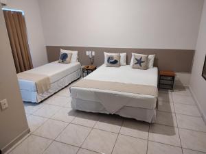 a room with two beds and a tiled floor at Hotel Guarda Mor in São Sebastião