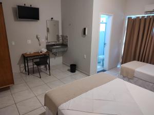 Zimmer mit 2 Betten, einem Schreibtisch und einem TV in der Unterkunft Hotel Guarda Mor in São Sebastião