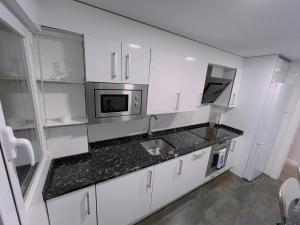 a kitchen with white cabinets and a sink and a microwave at Piso Atares Calle Alfonso in Zaragoza