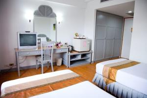 a bedroom with two beds and a desk with a television at Thumrin Hotel in Trang
