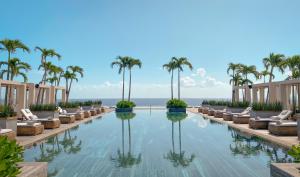 a swimming pool with palm trees and chairs at Impression Moxché by Secrets - Adults Only in Playa del Carmen