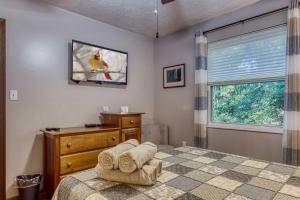 ein Schlafzimmer mit einem Bett, einer Kommode und einem Fenster in der Unterkunft Cozy Cabin with Mountain Views Near SkyLift Park! in Gatlinburg