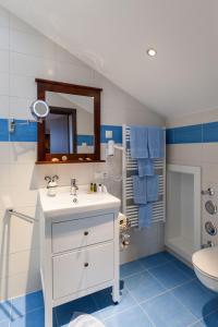 Un baño con lavabo, inodoro y espejo. en Vitusfort, en Füssen