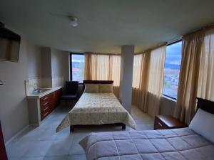 1 dormitorio con 2 camas, lavabo y ventanas en Hostal el Paraíso, en Cuenca