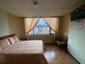 1 dormitorio con cama, ventana y silla en Hostal el Paraíso, en Cuenca