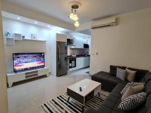 Diar El Rabwa Modern Apartment في شرم الشيخ: غرفة معيشة مع أريكة وتلفزيون