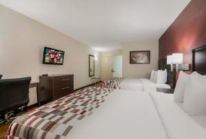 a hotel room with two beds and a desk at Red Roof Inn & Suites Knoxville East in Knoxville