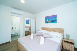 sypialnia z łóżkiem z białą pościelą i fioletowymi poduszkami w obiekcie Blue Bay Apartment w Dubrowniku