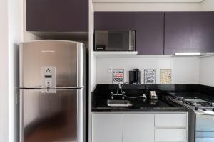 una cocina con nevera de acero inoxidable y armarios blancos en VA26 - Apartamento Luxuoso com Varanda Gourmet na Vila Carrão, en São Paulo