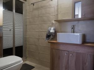 a bathroom with a white sink and a toilet at Melissinos Beachfront Apartments in Kómi