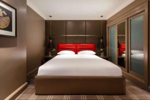 a bedroom with a large bed with a red headboard at Radisson Blu Edwardian Sussex Hotel, London in London