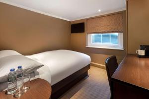 ein Schlafzimmer mit einem Bett und einem Tisch mit zwei Wasserflaschen in der Unterkunft Radisson Blu Edwardian Sussex Hotel, London in London