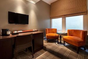 a room with two chairs and a desk and a tv at Radisson Blu Sussex Hotel, London in London