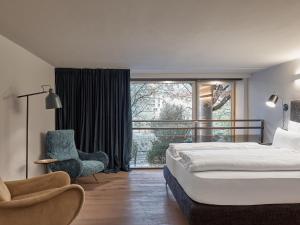 um quarto com uma cama, uma cadeira e uma janela em Parcloft em Merano