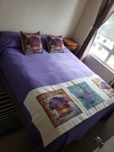 uma cama com um edredão roxo e almofadas em Departamento Tome em Tomé