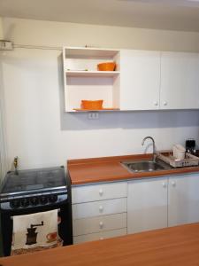 uma cozinha com armários brancos, um lavatório e um fogão em Departamento Tome em Tomé