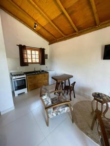 a living room with a table and a kitchen at Chalés e Suítes Campos de São João in Palmeiras