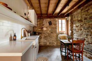 - une cuisine avec un évier et un mur en pierre dans l'établissement Randell's Mill - Adelaide Hills - Romantic Loft Stays, à Gumeracha