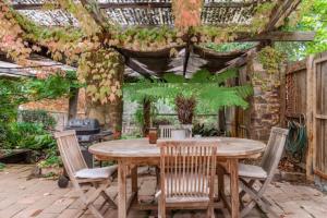 eine Terrasse mit einem Holztisch, Stühlen und einer Pergola in der Unterkunft Randell's Mill - Adelaide Hills - Romantic Loft Stays in Gumeracha