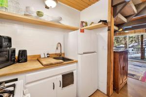 uma cozinha com armários brancos, um lavatório e um micro-ondas em 1946-Wolf Cub Cabin home em Big Bear Lake