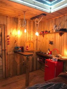 uma cozinha com paredes de madeira e um frigorífico vermelho em Cabana da Árvore - ForestPlace em Monte Verde