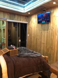 um quarto com uma cama e uma televisão na parede em Cabana da Árvore - ForestPlace em Monte Verde