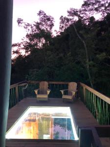 una terraza con 2 sillas y una piscina en Cabana da Árvore - ForestPlace, en Monte Verde