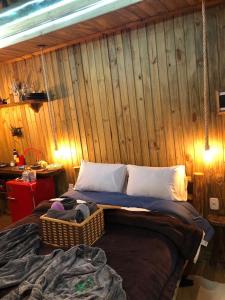 a bed in a room with a wooden wall at Cabana da Árvore - ForestPlace in Monte Verde