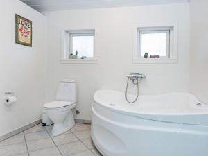 a white bathroom with a tub and a toilet at 8 person holiday home in Tarm-By Traum in Fjerbæk +24 photos